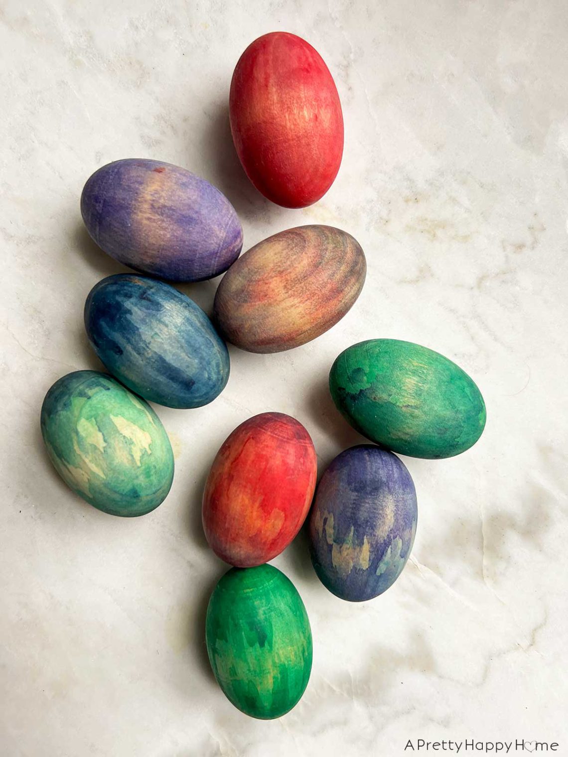 wood easter eggs stained in colorful ways using watercolor paint