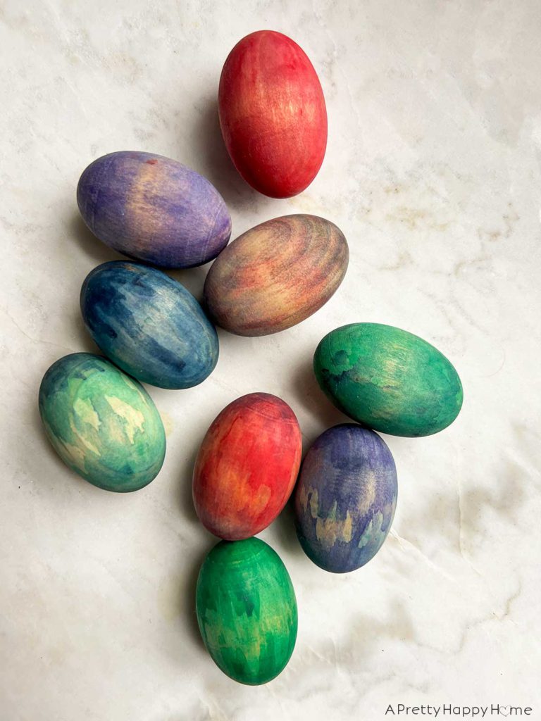 wood easter eggs stained in colorful ways using watercolor paint