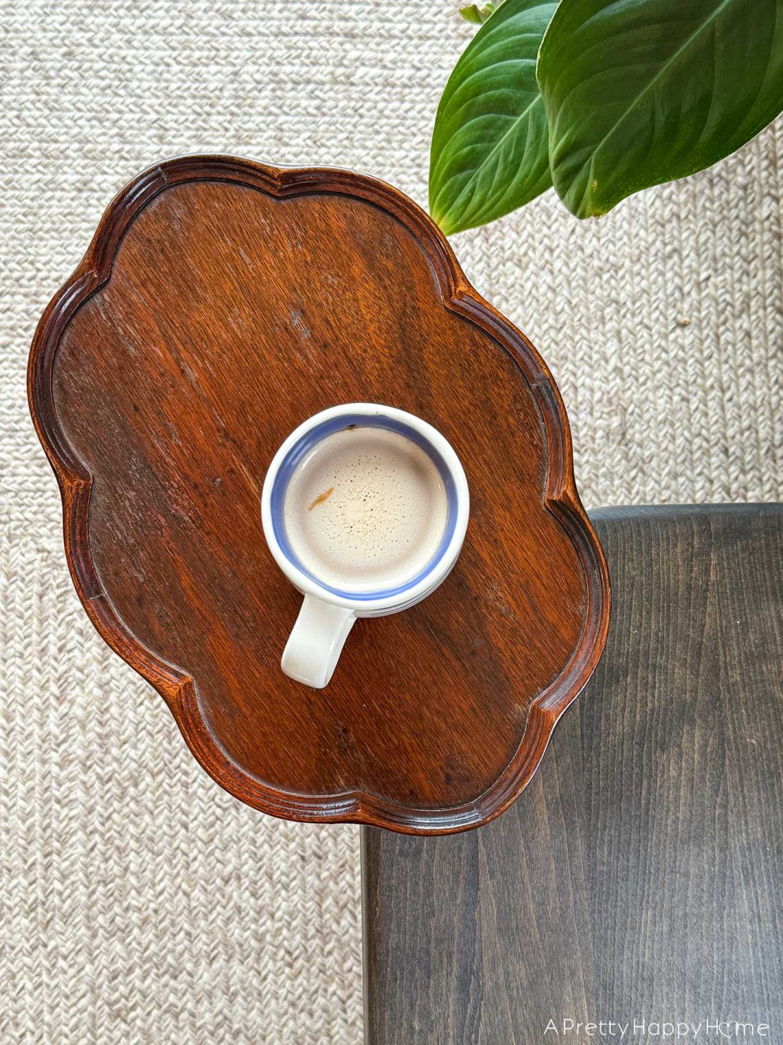 cup of coffee sitting on a scalloped edged wood drink table next to a wood bench