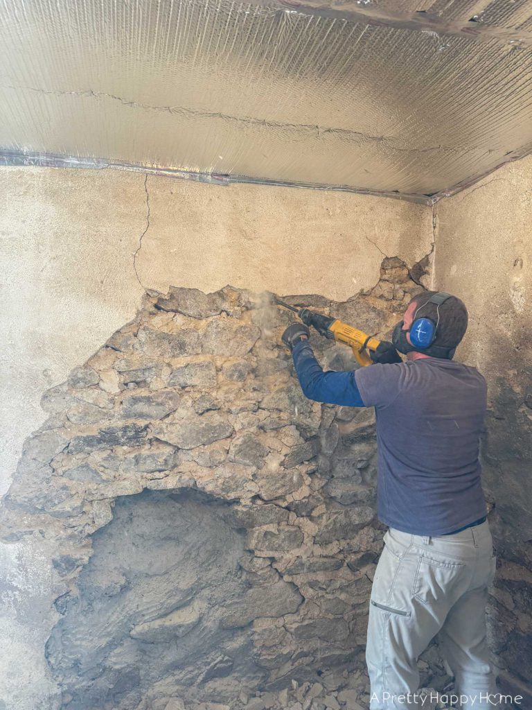removing and demoing old lime mortar off a fieldstone foundation wall using a chisel bit on a hammer drill
