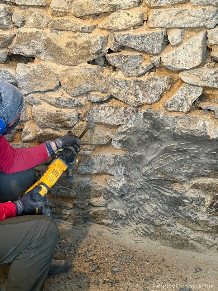 carriage house gym expansion demo a fieldstone wall to prepare for repointing removing concrete from a stone foundation with a chisel attachment on a hammer drill