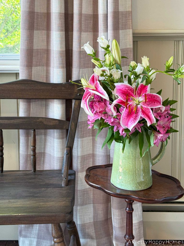 spring flowers in a vase sitting on a drink table by a wood bench