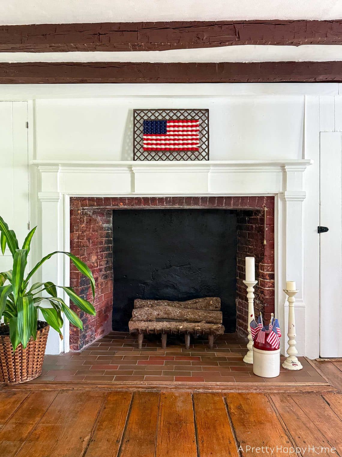 woven american flag on an antique grate made with yarn. It sits above a large fireplace in a colonial era home