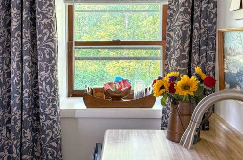 carriage house kitchenette with blue and white curtains to break up long narrow space