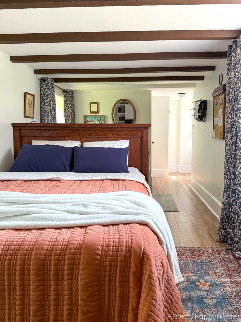 blue and white curtains in an old carriage house with an orange quilt 