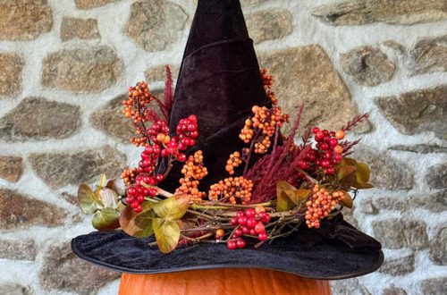 diy floral witch's hat sitting on a pumpkin in front of a stone wall