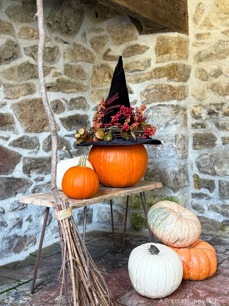 diy floral witch's hat sitting on a pumpkin in front of a stone fireplace