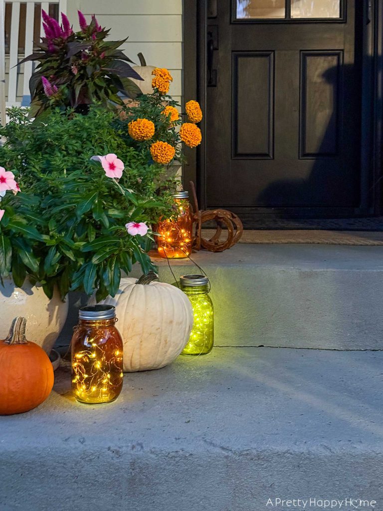 fall front porch at night with diy solar lanterns in colored glass jars solar mason jar lids with attached fairy lights