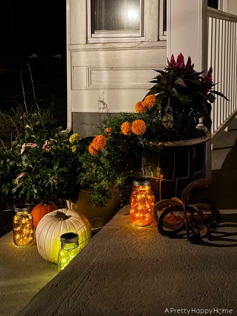 fall front porch at night with diy solar lanterns in colored glass jars solar mason jar lid with attached fairy lights