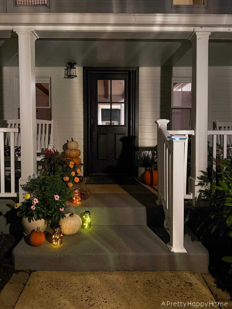 fall front porch at night with diy solar glass jar lanterns in colored glass solar jar lids with attached fairy lights