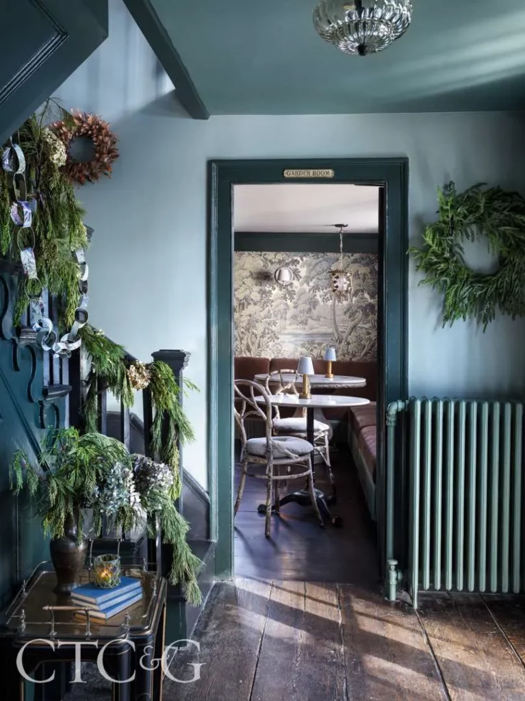 vignette from the lost fox inn and tavern of a blue ribbon with a staircase and green garland photo by ellen mcdermott via cottages and gardens on the happy list