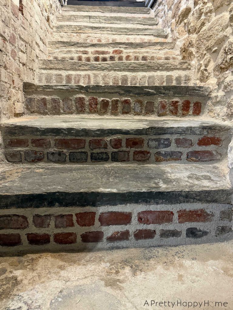 flagstone stairs to a basement with brick risers. the sides of the stairwell are part fieldstone, part brick. the stairs are a little wet as they had just been repointed with new lime mortar.
