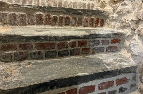 flagstone stairs to a basement with brick stair risers. the walls of the stairwell on fieldstone.