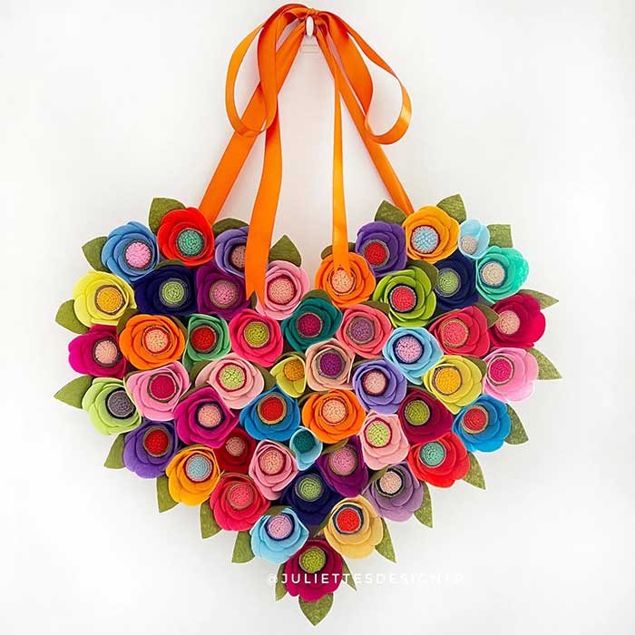 heart shaped wreath made out of colorful heart flowers and hanging from an orange ribbon. wreath is made by etsy shop juliettesdesigntr and shown here on the happy list