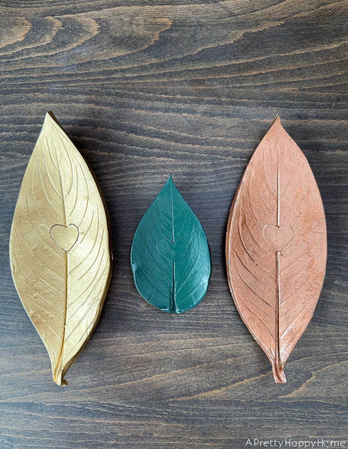 three polymer clay oven bake leaf trinket dishes in a row. One is gold, a smaller one is green, the third one is copper.