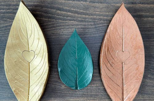three polymer clay oven bake leaf trinket dishes in a row. One is gold, a smaller one is green, the third one is copper.