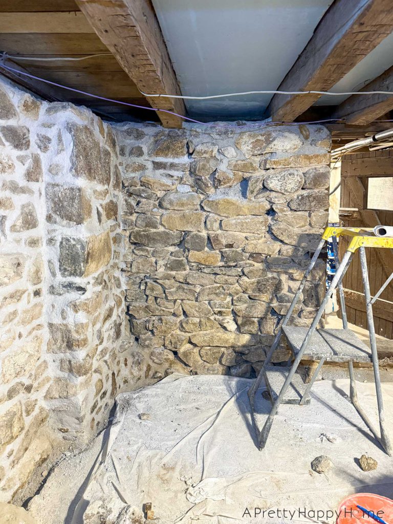 picture of a basement workshop stone repointing project showing a partially chipped out stone wall being repointed with reproduction historic lime mortar