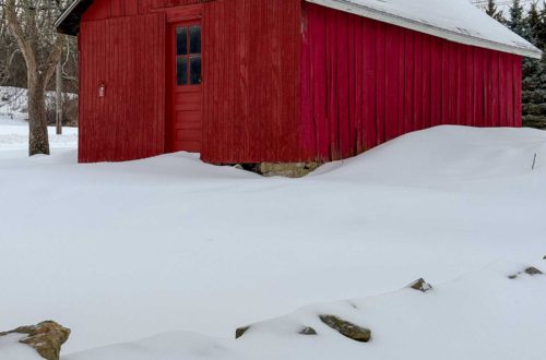 red barn in the snow. there is a door on the end of the door with a glass window.