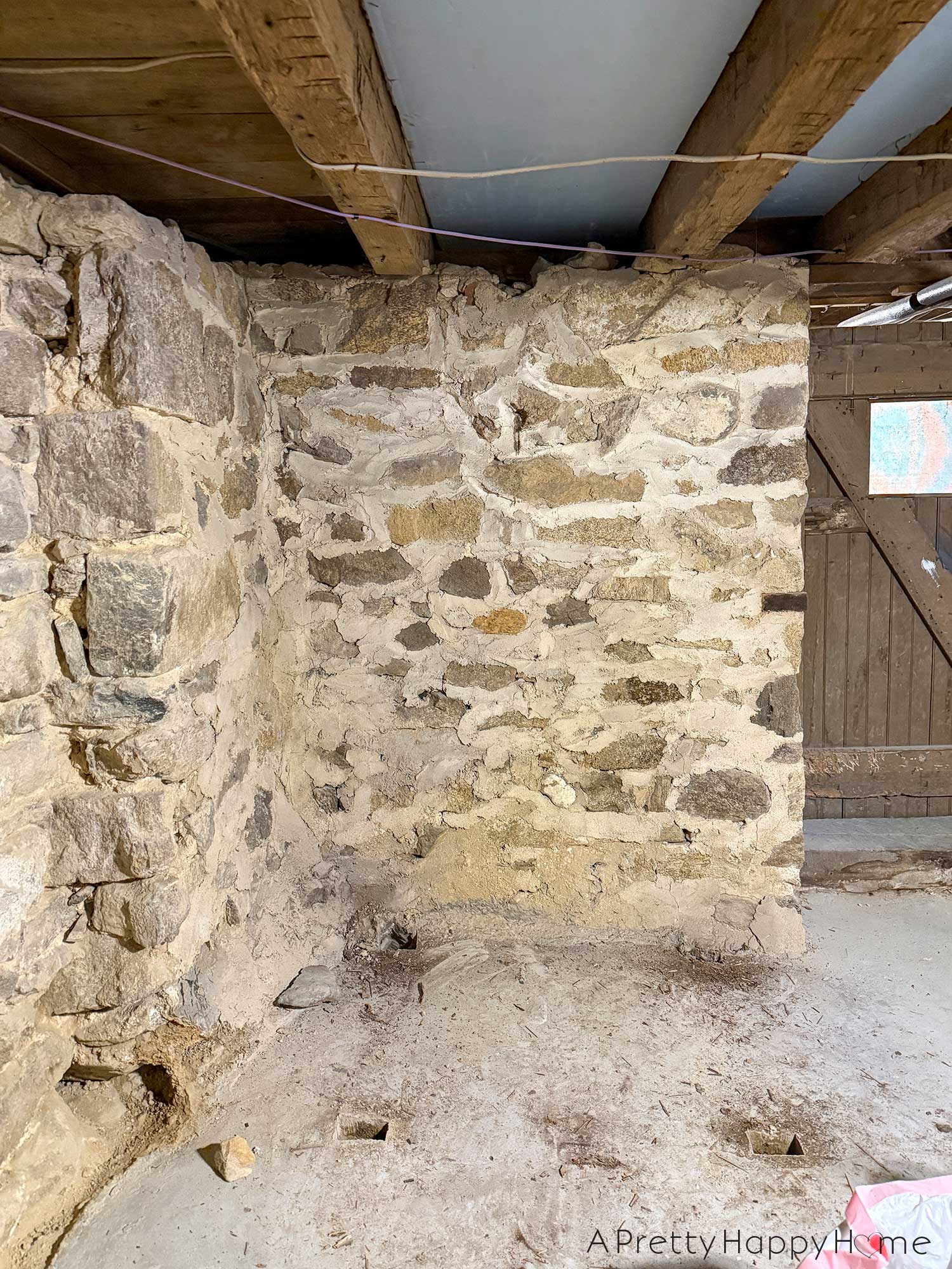 Stone foundation walls in a basement of a 1780s home that desperately need to be repointed and repaired after previous patches with concrete