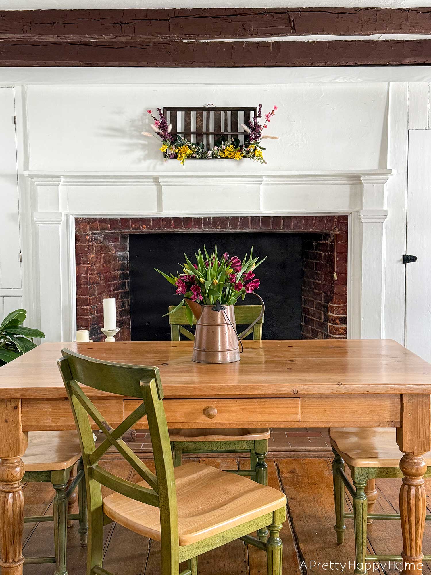 diy repurposed berry crate spring wreath using a vintage wood berry field flat or berry basket carrier. It's hanging on the wall with sprays of pink, yellow, and purple faux flowers attached to it.