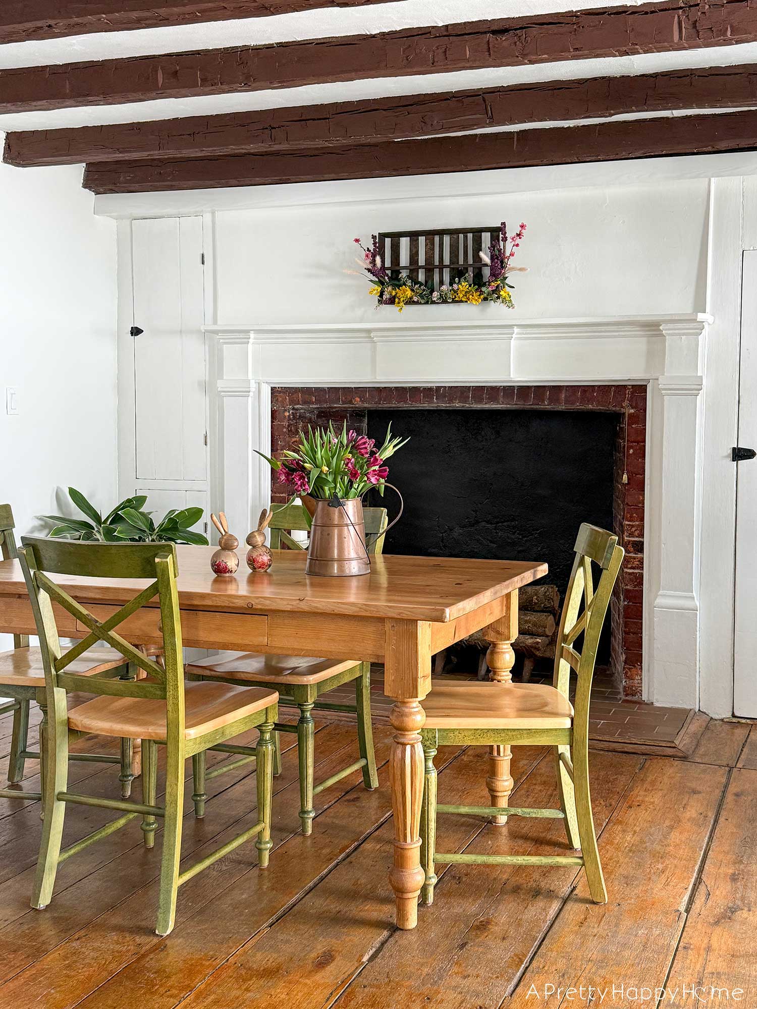 diy repurposed berry crate spring wreath using a vintage wood berry field flat or berry basket carrier. It's hanging on the wall with sprays of pink, yellow, and purple faux flowers attached to it.