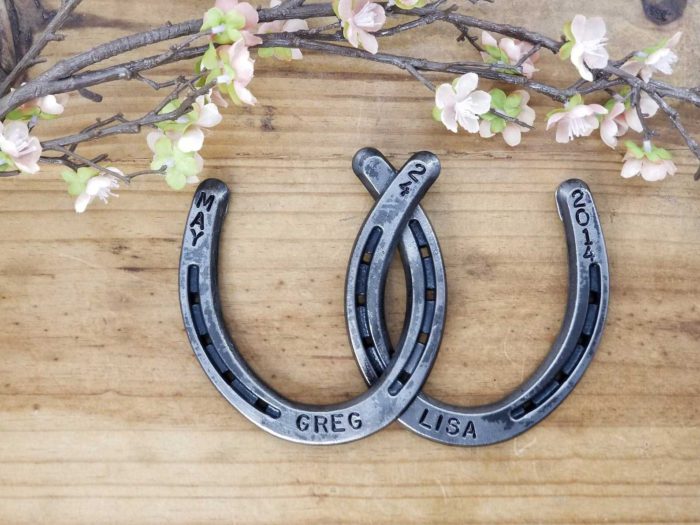 two intertwined horseshoes for a wedding stamped with the wedding date and names of the married couple from etsy shop luckyamericandesigns