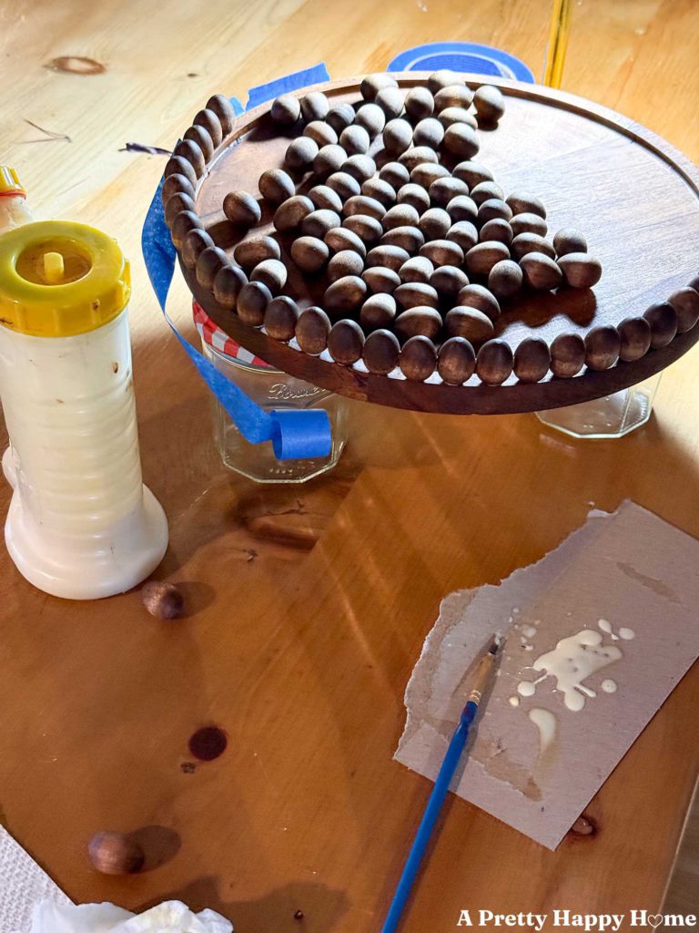 Mini wood eggs being glue with wood glue to a wood pedestal.