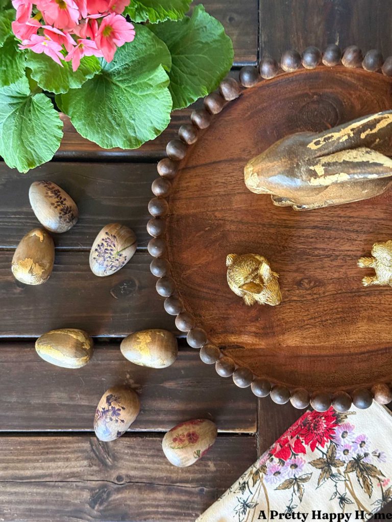 vignette showcasing a diy wood pedestal with mini wood egg trim around the edge. the mini wood eggs are stained to match the wood tone of the wood stand