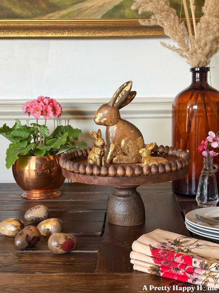 vignette showcasing a diy wood pedestal with mini wood egg trim around the edge. the mini wood eggs are stained to match the wood tone of the wood stand