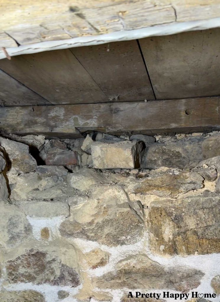 an interior stone foundation wall in the process of being repointed, the top of which is unstable and needs to be rebuilt