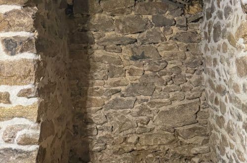 an interior stone foundation wall in the process of being repointed, the top of which is unstable and needs to be rebuilt