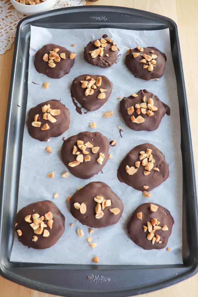 parchment covered sheet pan holding chocolate covered frozen yogurt bites topped with chopped peanuts recipe by Homemade Heather