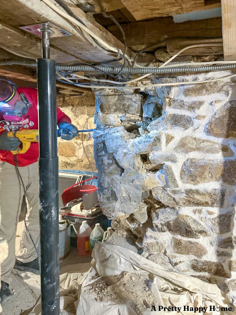 Chipping off concrete from a 1780s stone foundation with a hammer drill. The concrete was used to poorly repair a stone foundation and needs to be removed to keep the foundation structurally sound.