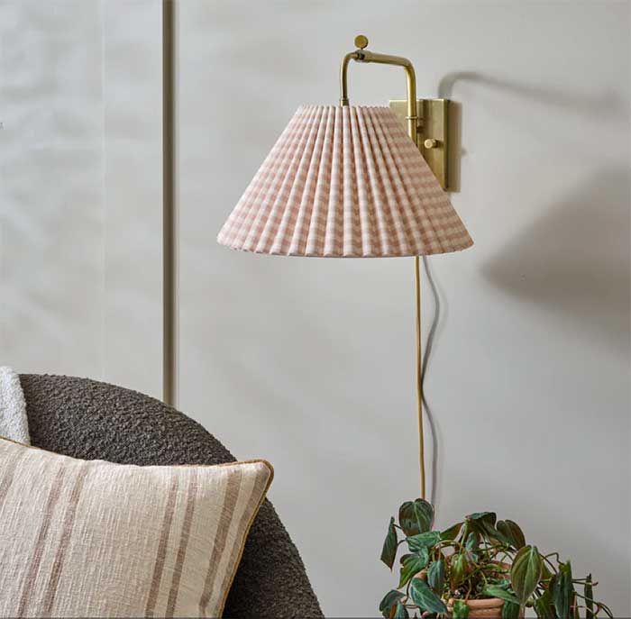 brass swivel sconce with a gingham lamp shade in a light tan color