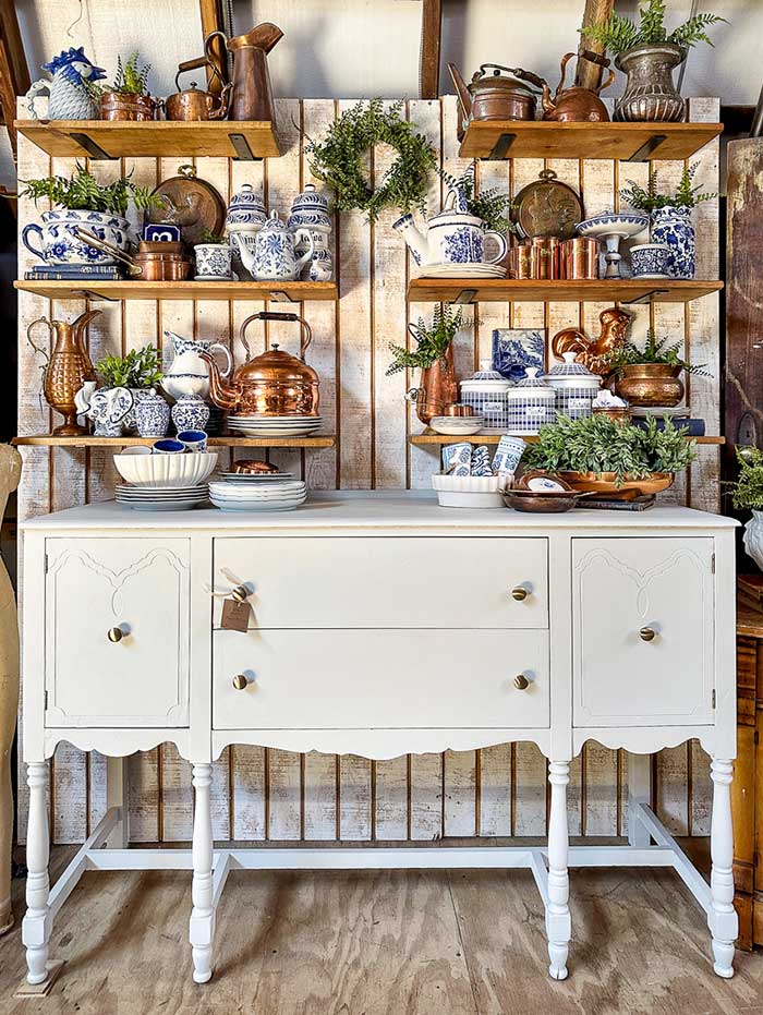 rustic shelves above a white sideboard that hold a collection of vintage copper serving ware and vintage chinoiserie at the Lily and Birch Market in Maryland