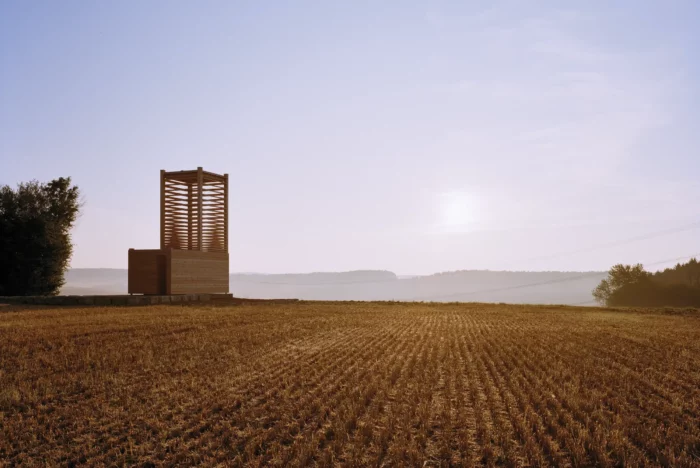 wooden field chapel built in Bodigheim, Germany, that sits in a remote field with the sun sitting low on the horizon in the distance. Photo by Brigida Gonzalez for Frederic Magazine.