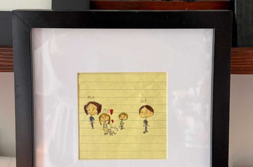 family portrait framed and drawn by a child on yellow lined paper. Above the picture is the same family painted on peg dolls.