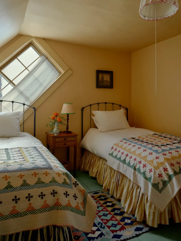 witch window in a yellow child's bedroom in a vermont home. The twin beds have colorful quilts on the bed and the floor is painted a sage green. Photo by belle morizio via domino.