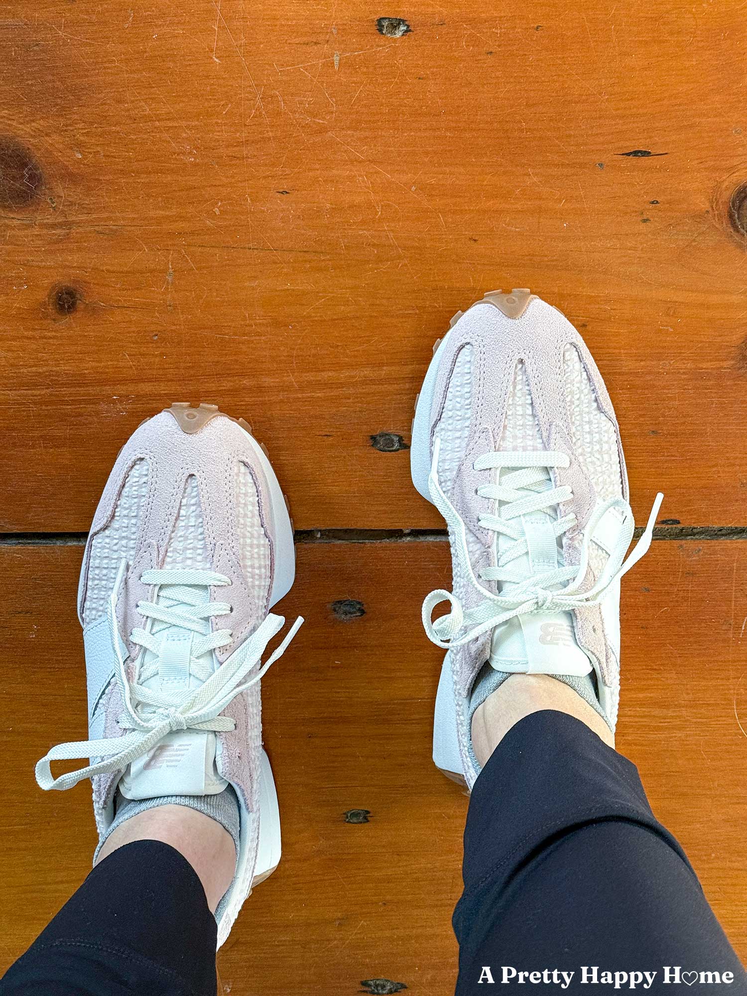 woman wearing new balance 327 tennis shoes in pink gingham pattern standing on wood floor