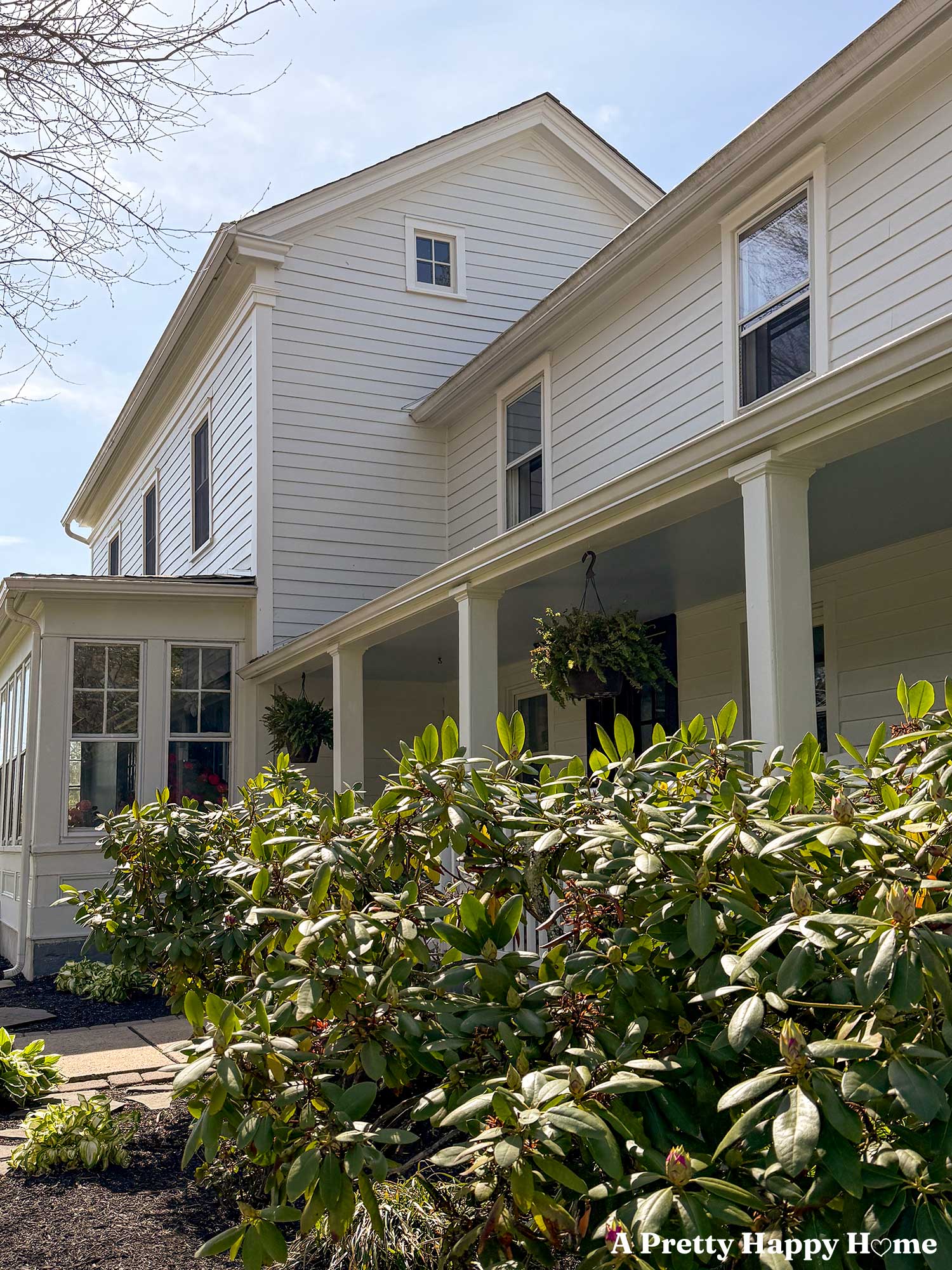 Greek revival style home with a sun porch and covered front porch that is painted white. Photo specifically shows the repaired gable return on the roof eave.
