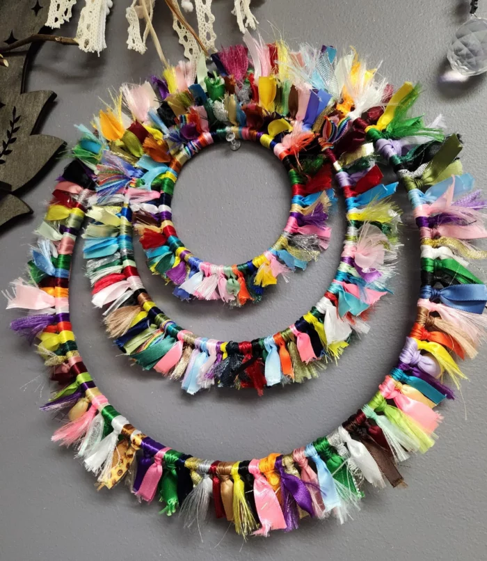 three wreaths made from colorful ribbon scraps tied around the wreath form via etsy shop fox moon finery