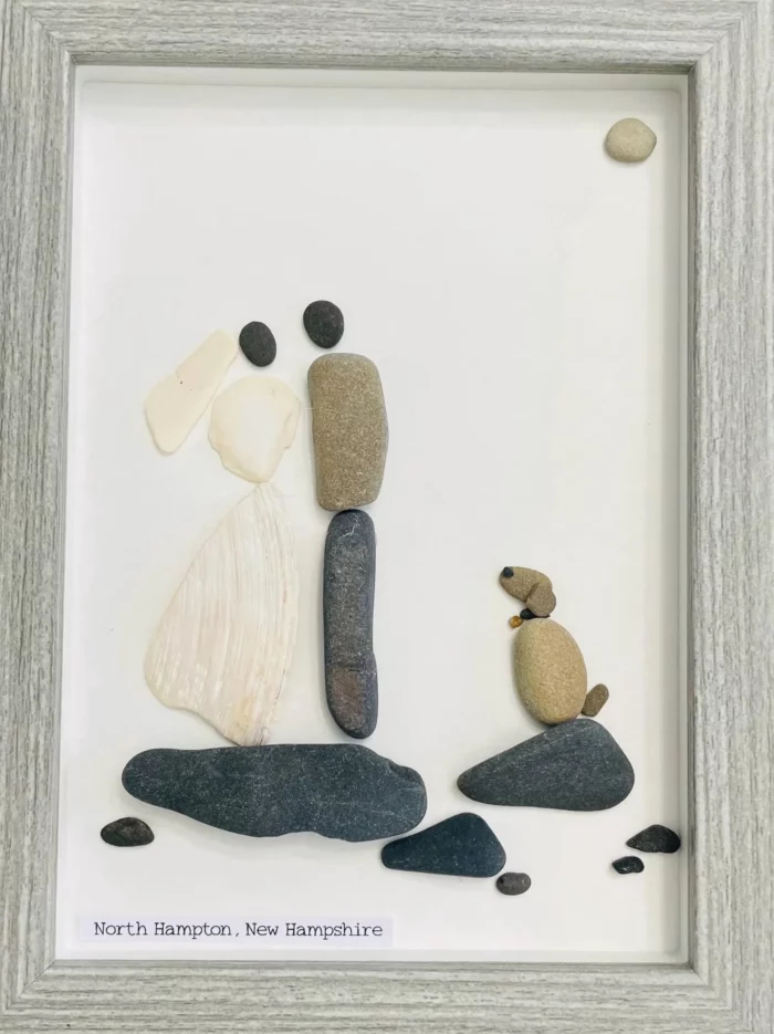 custom wedding portrait made with small pebbles showing a bride, groom, and a dog standing on small dark stones and made by etsy shop mother and son stone art