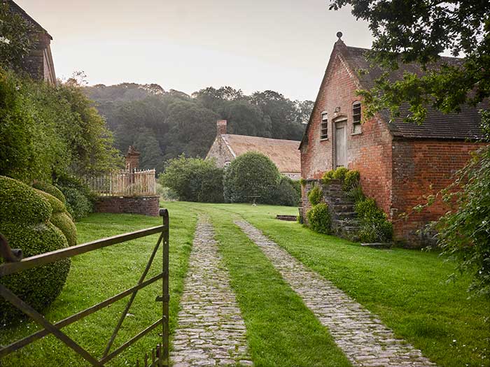 cobblestone cart tracks lead past brick buildings on a historic estate