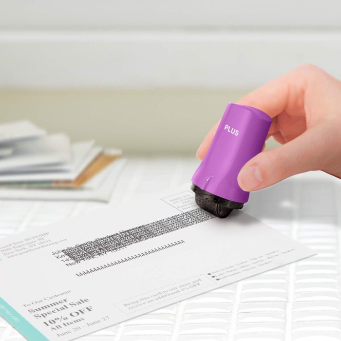woman using a security stamp with a purple handle to block obscure identifying info on mail