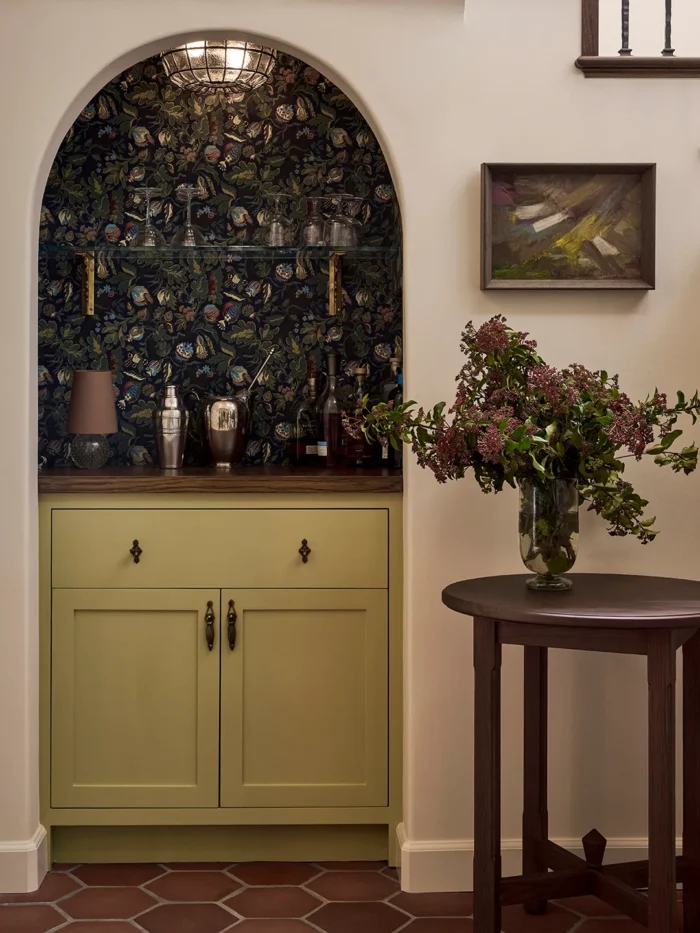 photo by dan arnold for domino of a colorful under-the-stairs nook with a yellow base cabinet, wood top, colorful wallpaper, and an arched doorway opening.