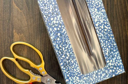 empty tissue box with a pretty blue print sitting next to gold-handled scissors and a glue stick in preparation to epicycle the tissue box cardboard into cute crafts