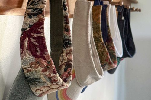 row of colorful visors hanging from a wood peg rail