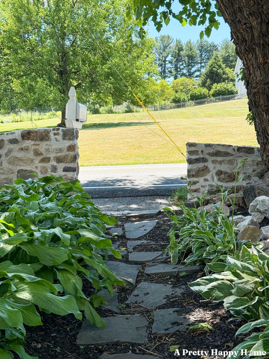 Two sloped fieldstone walls of different heights separated in the middle by a flagstone path