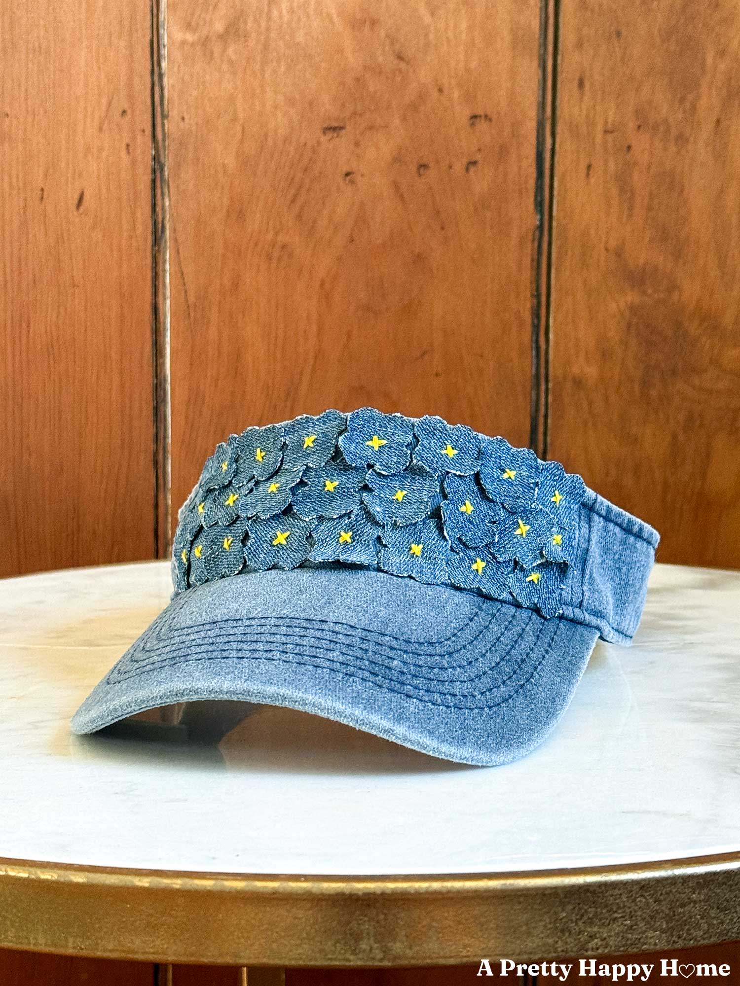 denim visor with small denim flower stitched to the headband with yellow embroidery thread