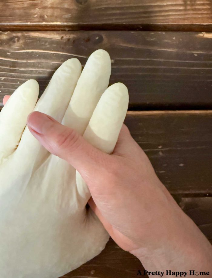 real hand holding the hand of a fake hand made out of a white latex glove filled with rice